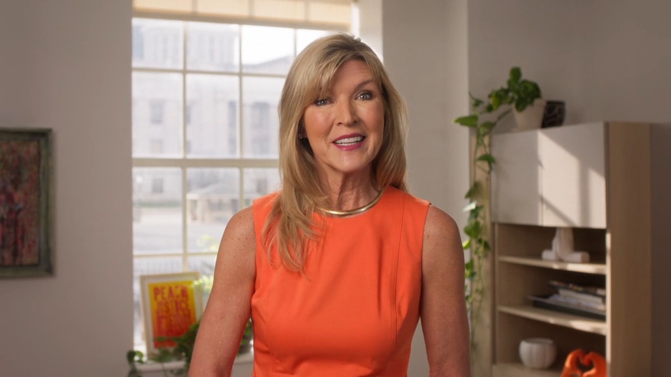 Presenter in orange smiling in the YWCA Columbus anniversary film